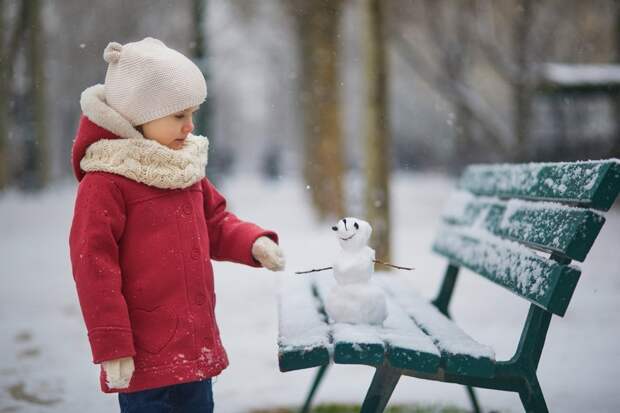 Девочка слепила снеговика на скамейке