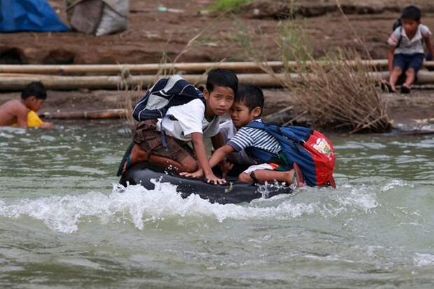 Дети в школу добираются по бурлящей реке.