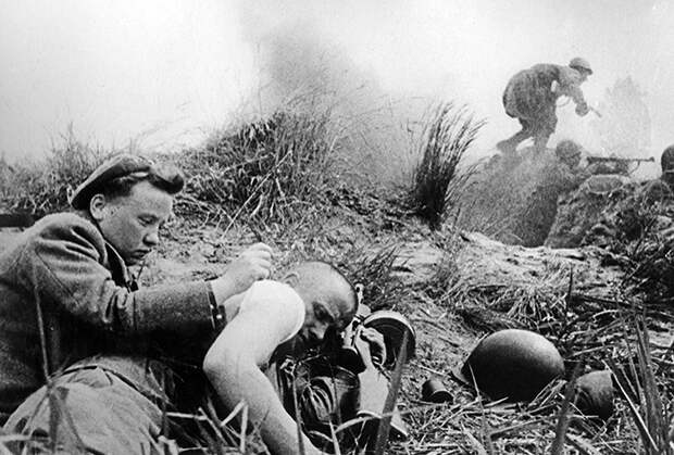 Санинструктор перевязывает солдата во время боев на Ленинградском фронте