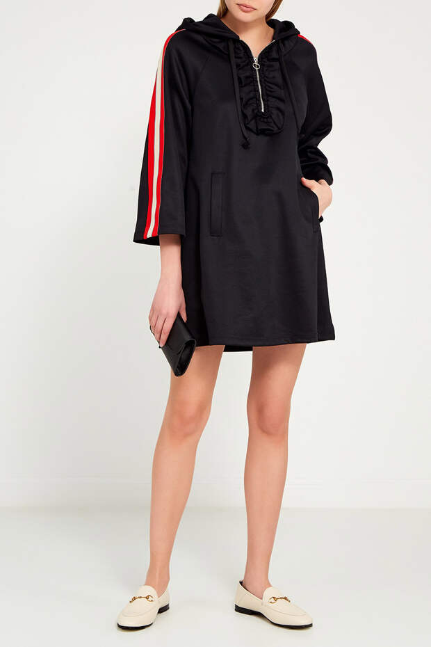 Черное мини-платье оверсайз от Gucci А-силуэта с длинными рукавами реглан, отделанными контрастной красно-белой полосой. Капюшон объемный на кулиске, на юбке – прорезные карманы. Спереди – глубокий вырез на молнии, обрамленный широкой оборкой в тон. Черное мини-платье оверсайз от Gucci А-силуэта с длинными рукавами реглан, отделанными контрастной красно-белой полосой. Капюшон объемный на кулиске, на юбке – прорезные карманы. Спереди – глубокий вырез на молнии, обрамленный широкой оборкой в тон.
