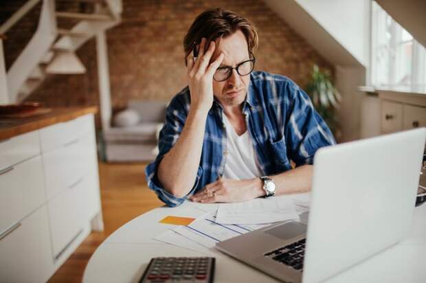 A person at a desk holding their head.
