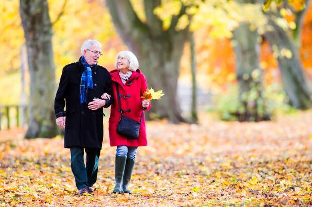 Senior couple walking on leaves in the fall