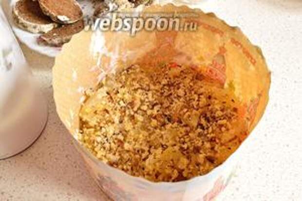 На первый слой пряников положить кусочки ананасов. Сверху ананасы посыпать измельченным грецким орехом.
