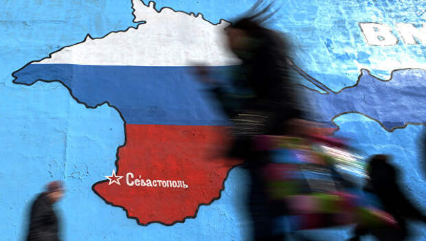 Прохожие у нарисованной на стене карты Крыма в цветах российского флага. Архивное фото
