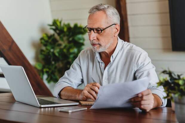 A person at a laptop holding documents.