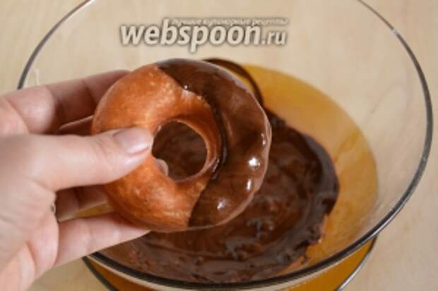 Смешайте шоколад с сахарной пудрой и растопите на водяной бане. Обмакните половинку каждого пончика в глазурь.