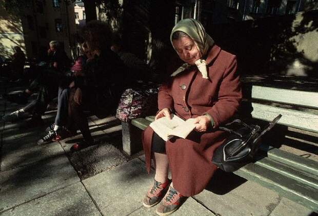 Elderly Woman Sitting on Bench Reading Book