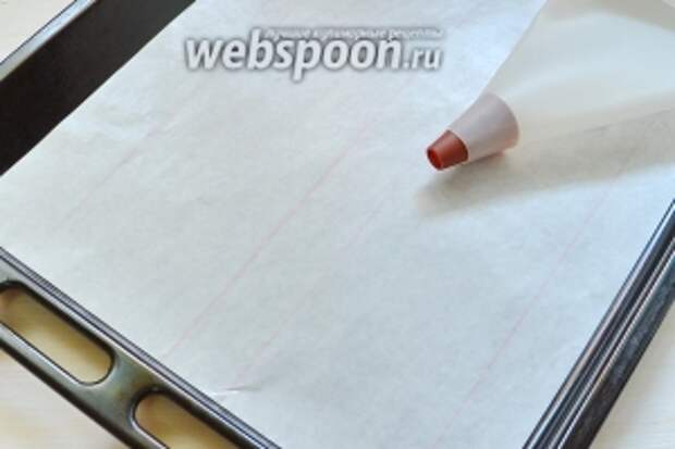 Приготовим сразу кондитерский мешок, противень и пергамент. На листе нарисуем 2 полосы шириной 9 см и перевернём нарисованными линиями вниз.