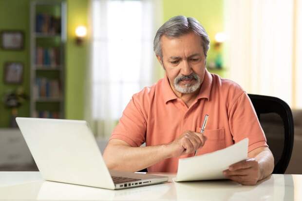 Serious person holding pen and looking at document.