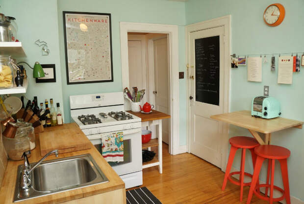 Маленькая кухня, выполненная в стильном мятном цвете, обставленная компактной деревянной мебелью.