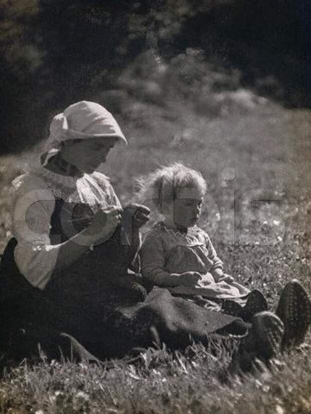 ca. 1931 --- Mother and daughter sitting in a meadow. The woman is knitting. --- Image by ? Alinari Archives/CORBIS