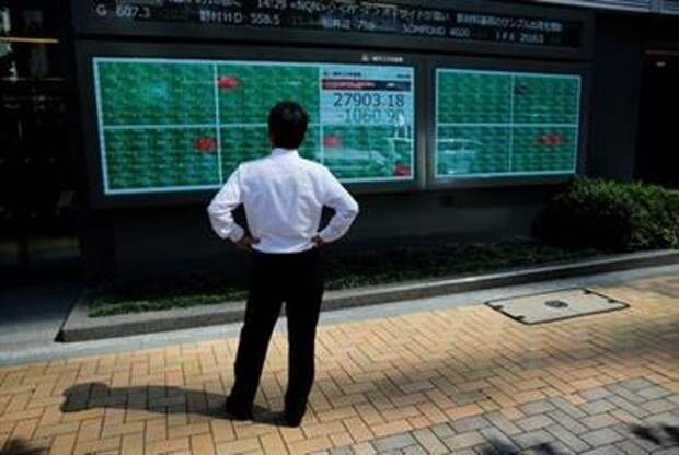 FILE PHOTO: A man watches an electric board showing Nikkei index outside a brokerage at a business district in Tokyo, Japan, June 21, 2021. REUTERS/Kim Kyung-Hoon/Files 