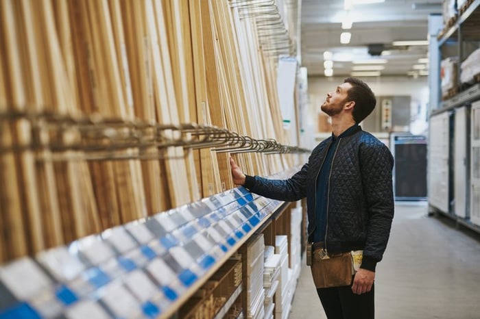A man selecting pieces of wood in a large home improvement store.
