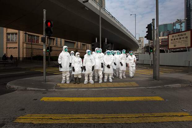 Health officers in full protective gear wait to cross a road near a wholesale poultry market in Hong Kong January 28, 2014. Hong Kong began culling 20,000 chickens and suspended imports of fresh poultry from mainland China for 21 days on Tuesday after the discovery of the H7N9 bird flu virus in a batch of live chicken from the southern province of Guangdong. REUTERS/Tyrone Siu (CHINA - Tags: HEALTH ENVIRONMENT SCIENCE TECHNOLOGY ANIMALS TPX IMAGES OF THE DAY) - GM1EA1S0YMZ01