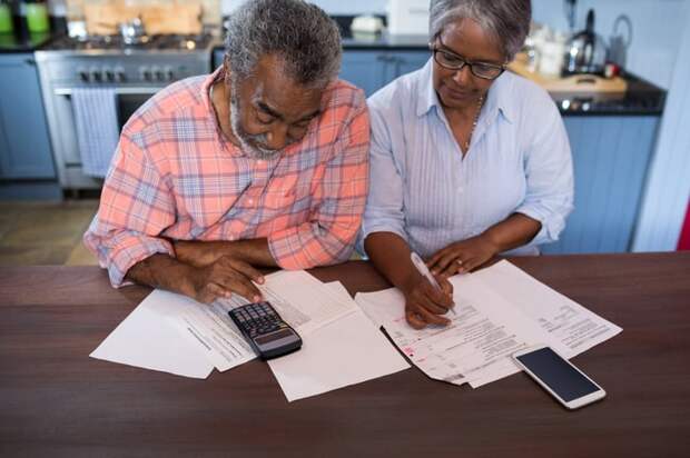 Two people looking at documents and a calculator.