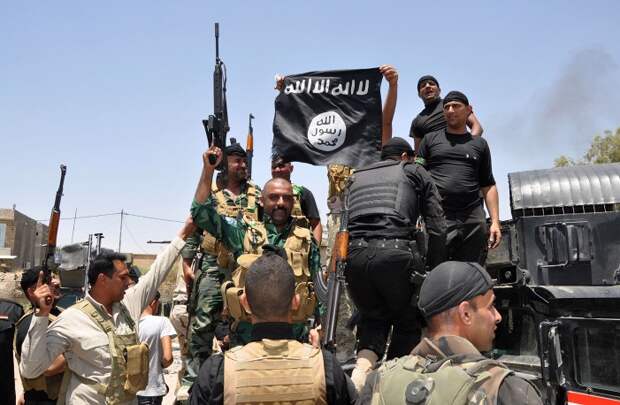 Несмотря на потери в Мосуле и провинции Найнава, иракская армия продолжила сопротивление. На фото: иракские военные с флагом ИГ, захваченным в ходе боев, июнь 2014 г.