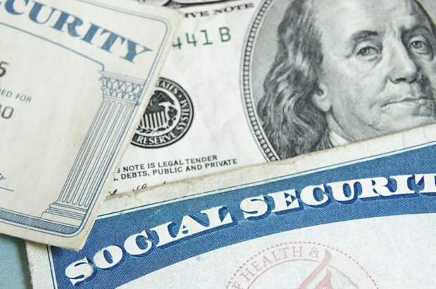 Two Social Security cards next to a $100 bill.