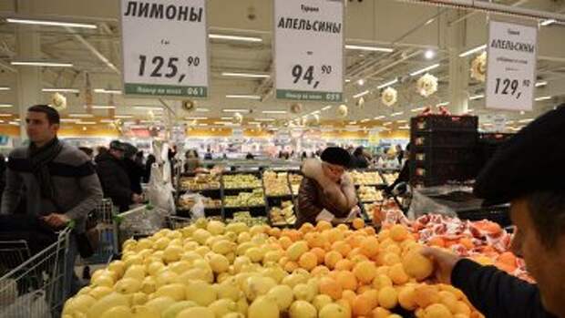 Покупатели у прилавка с лимонами и апельсинами из Турции в торговом зале гипермаркета Глобус