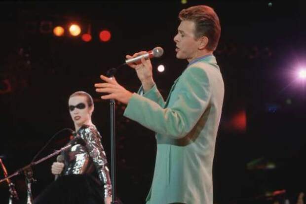Singer David Bowie performs the Queen song "Under Pressure" with Annie Lennox, wearing black mask makeup around her eyes, at the Freddie Mercury Tribute Concert. The concert paid tribute to Queen lead singer Freddie Mercury who died of AIDS in 1991.