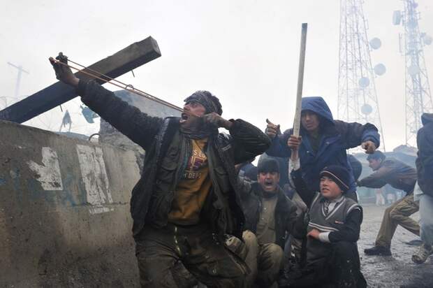 An Afghan man aims a sling shot toward U