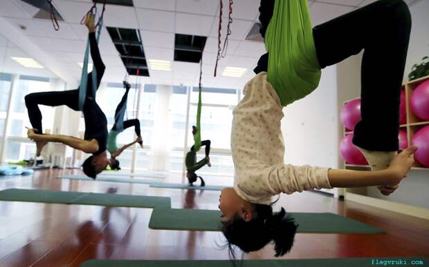 Студенты практикуют антигравитационную йогу в тренировочном зале в городе Ханчжоу, провинция Чжэцзян.