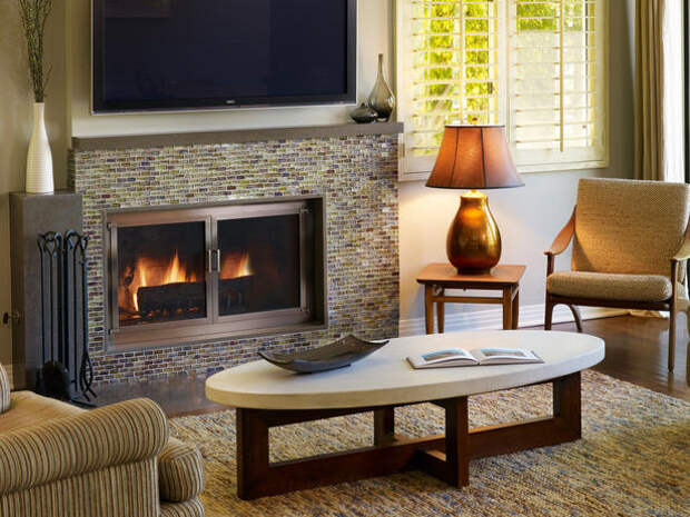 Living room with fireplace, rug on a hardwood floor, coffee table, chairs, table, and lamp.