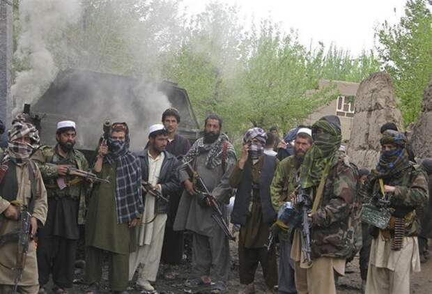 Taliban insurgents pose in front of a burning German military vehicle in Isaa Khail village of Char Dara district of the northern Kunduz Province