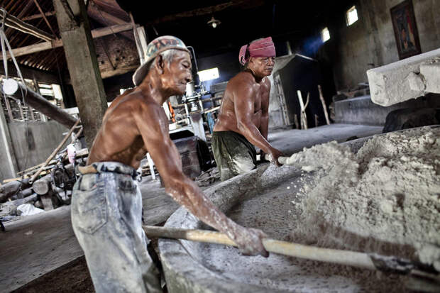 Рабочие постоянно выравнивают лопатами сырье в «мукомольном аппарате», чтобы было равномерное давление