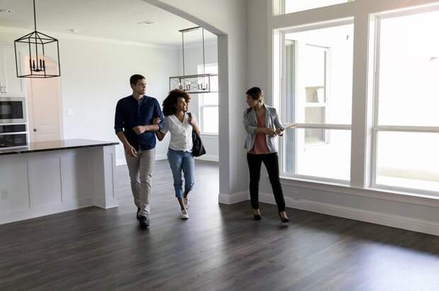 Two people viewing the interior of a house with a realtor.