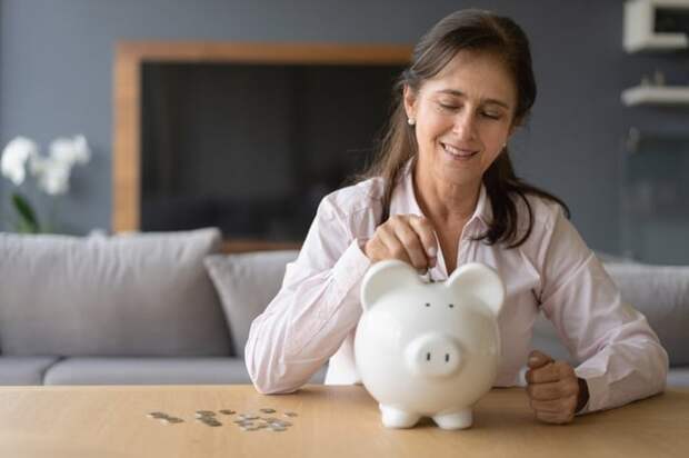 Woman putting coins into piggy bank