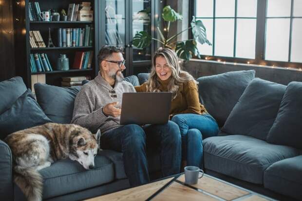 Two people sitting on a couch looking at a laptop.