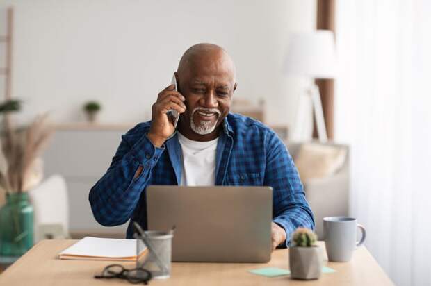 Person looking at a laptop and talking on the phone.