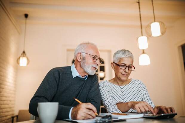 A retired man and woman review their finances together while seated a table.