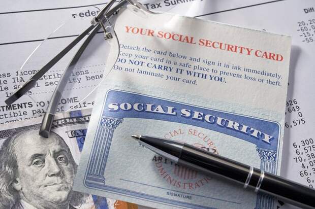 A Social Security card sitting atop a $100 billion and a financial document.