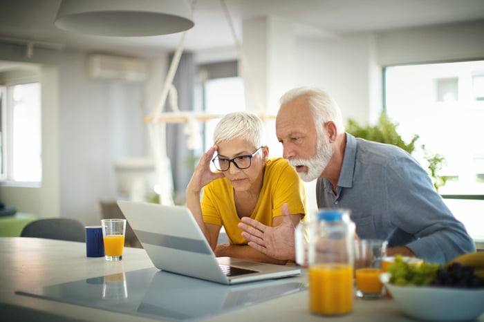 Two people with stunned expressions on their faces looking at a laptop.