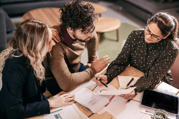 Young couple going over paperwork with female professional.