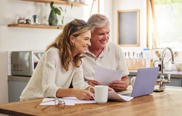 Two smiling people at a laptop.