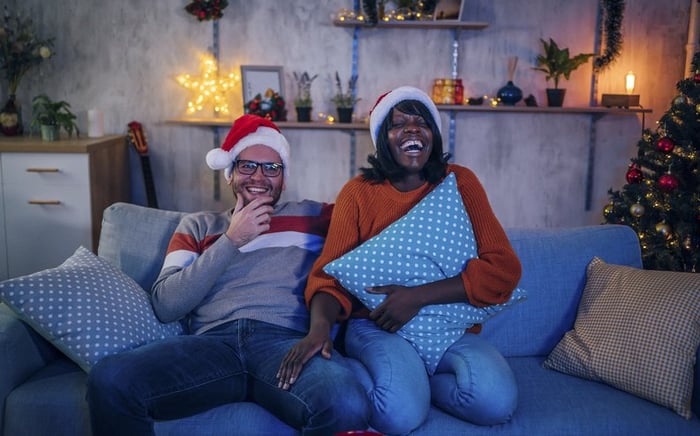 Couple in Santa hats watching a movie on the couch