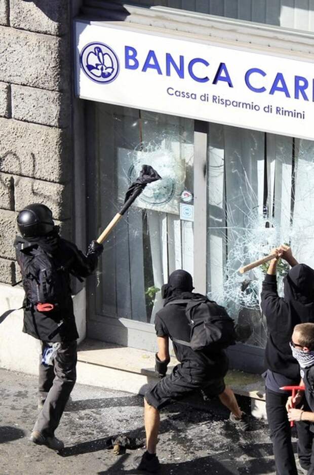 Demonstrators attempt to break through the entrance of a bank branch during a demonstration against banking and finance in Rome