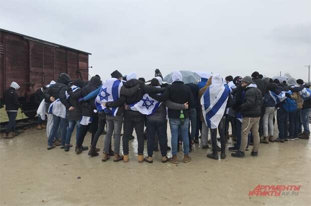 У вагона без окон на путях в Биркенау стоят израильтяне. Завернувшись в национальные флаги, они поют еврейскую поминальную молитву – кадиш.