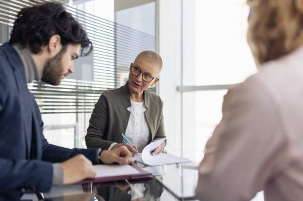 A woman reviews a couple's financial statments at a round conference table