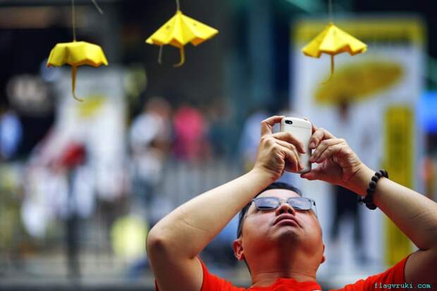 Мужчина фотографирует миниатюрные бумажные зонтики – символ движения за демократию, которые активисты развешали в торговом районе Монгкока, Гонконг.