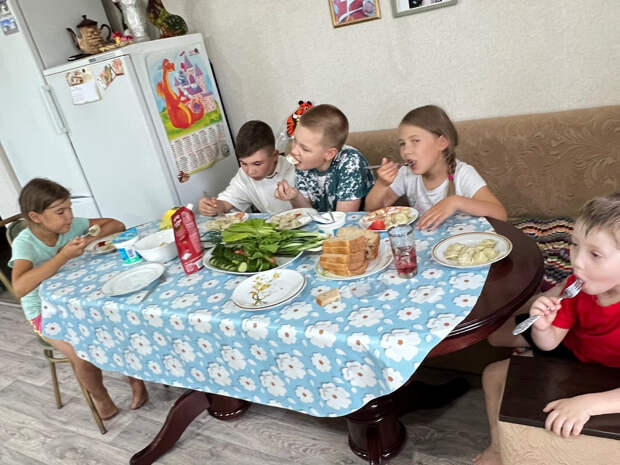 Внуки и правнук бабушки уплетают пельмени. На скатерть не смотрите, стол раздвинули, она оказалась короткой, надо заменить
