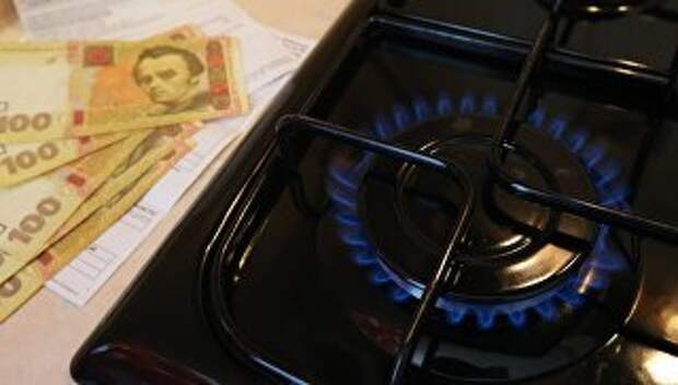 Горящая газовая конфорка и денежные купюры Украины