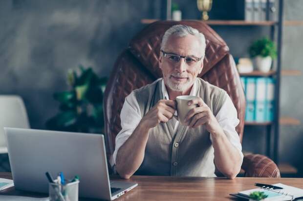 Rich older man sitting in a leather chair at his desk.
