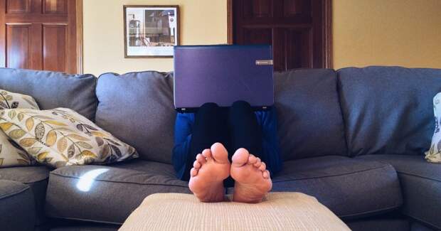 Мужчина на диване за ноутбуком