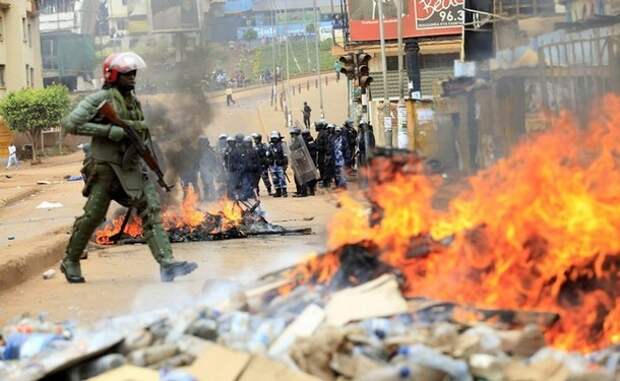 A Ugandan military police officer walks past a barricaded road in Kampala