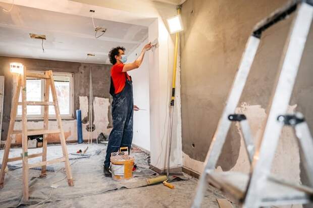 A person putting up drywall in a home renovation.