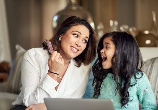 A parent teaches their child about credit cards through buying something online.