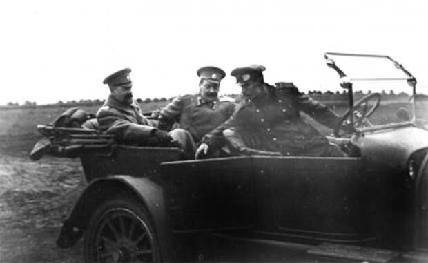 На фото: великий князь Александр Михайлович (крайний слева) и сопровождающий его офицер в автомобиле во время приезда на аэродром. Авиационная рота и V дивизион при XII армии. 1915 год